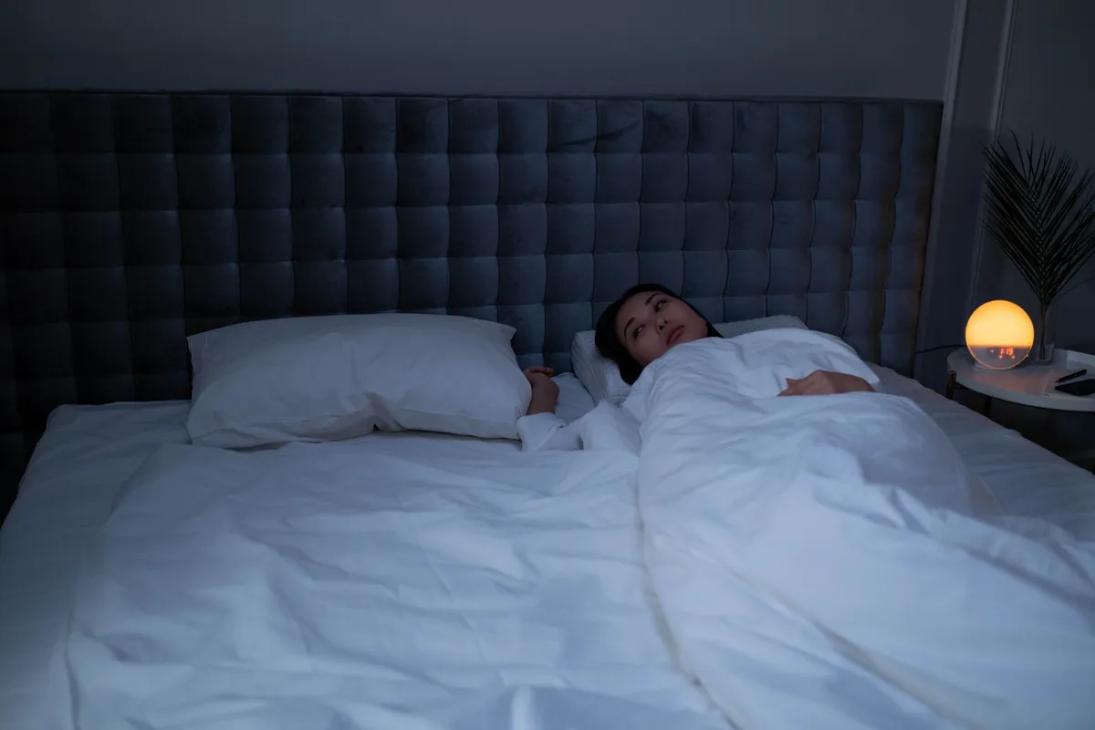 A woman lying awake at night, a common betrayal trauma symptom