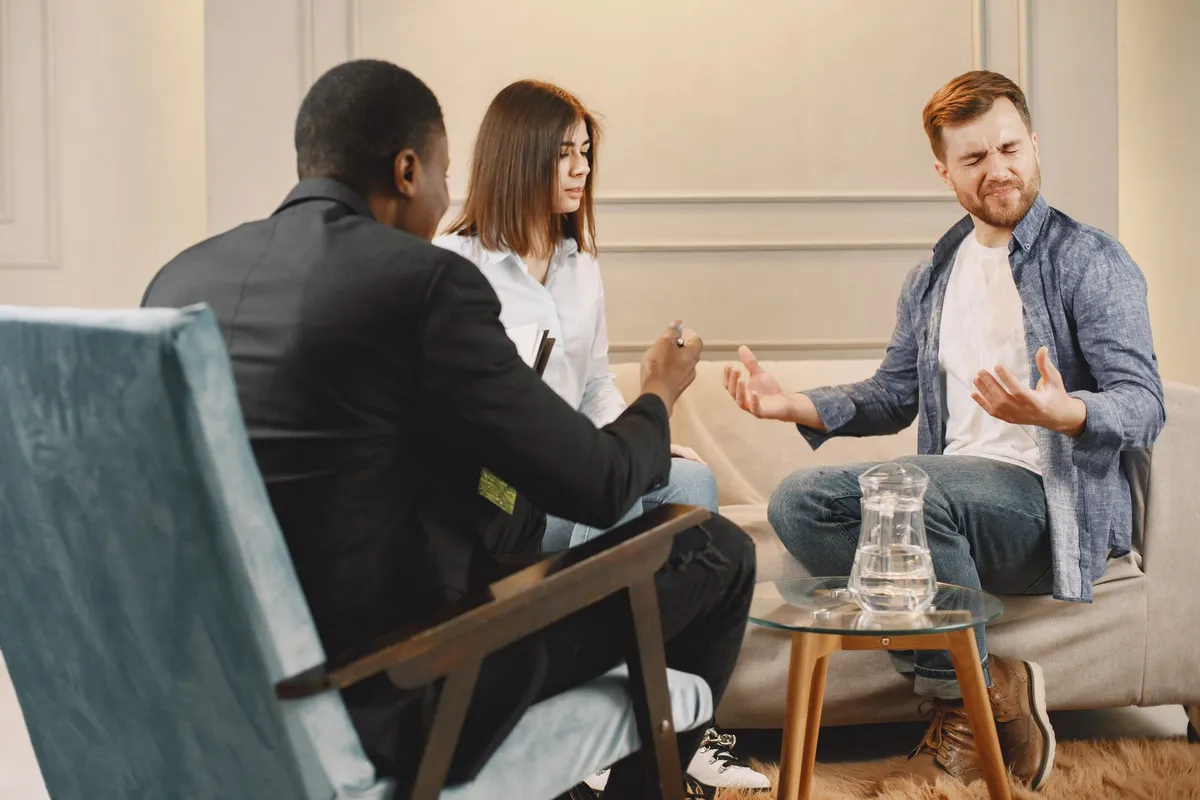 A couple sitting apart during a counselling session about a marriage break up