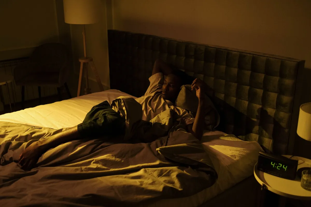 A man lying awake alone in bed in the early hours
