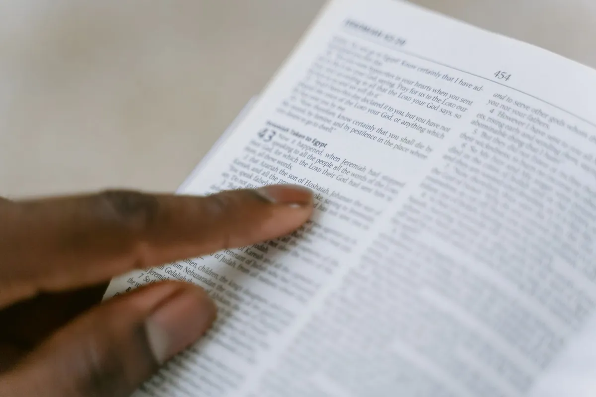 A hand resting on the open page of a Bible