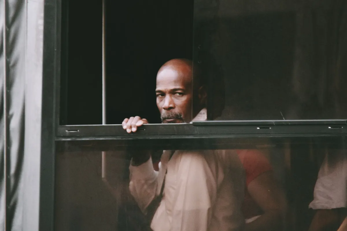A man standing at a window in early morning light, facing the question of how he can rebuild trust