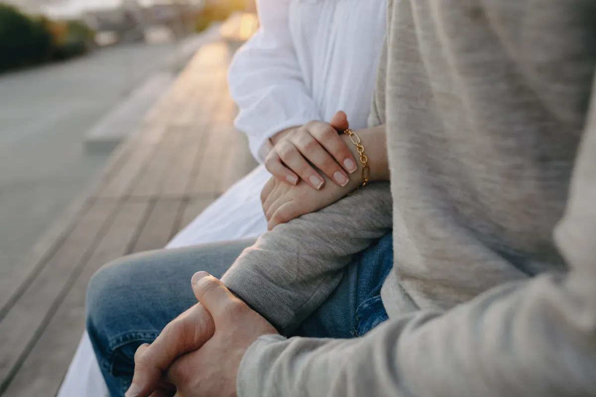 A couple sitting together on a bench outdoors