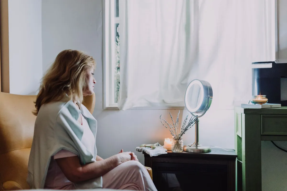 A woman sitting quietly in soft morning light, beginning to heal from betrayal trauma