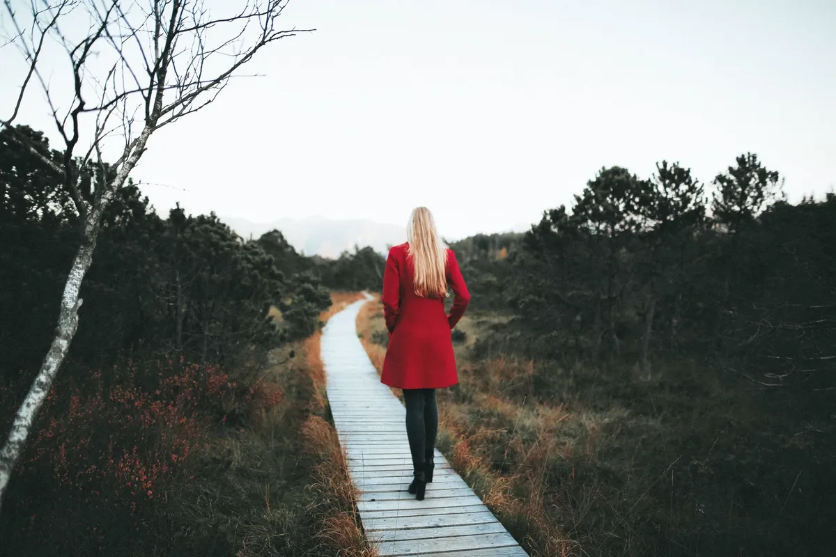 A woman walking outdoors on a quiet trail, part of healing from betrayal trauma