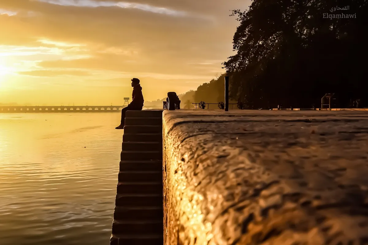 A man sitting alone on outdoor steps in the evening, thinking