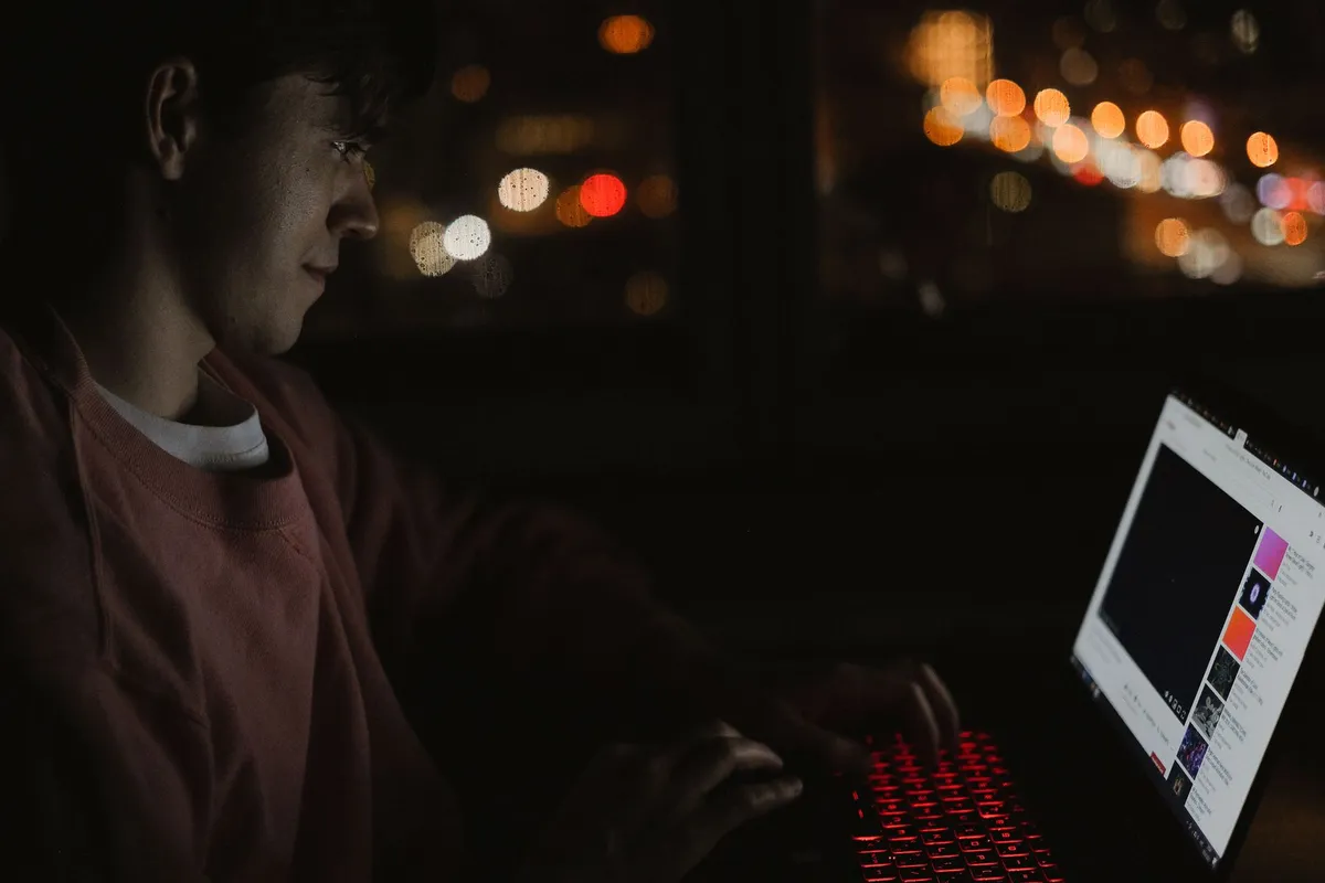 A man alone at a laptop in a dark room at night, illustrating a husband addicted to porn