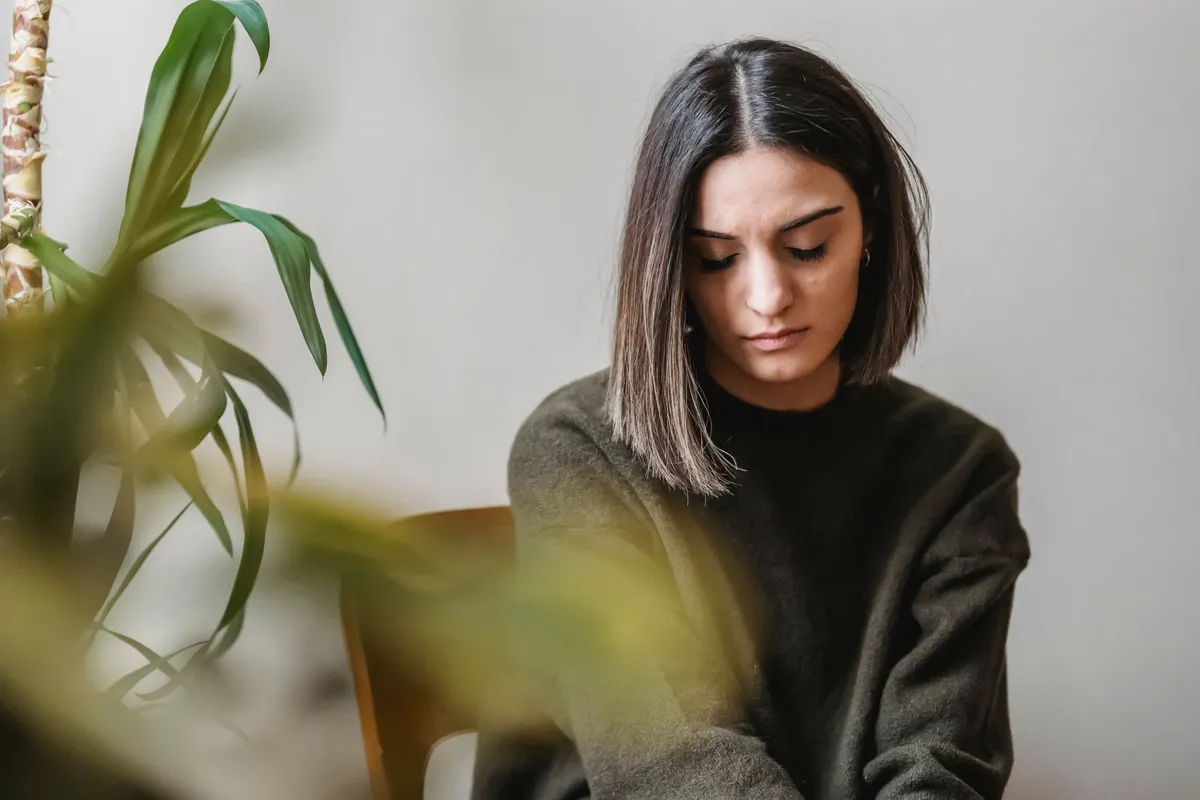 A woman sitting alone at home, processing the discovery that her husband is addicted to porn