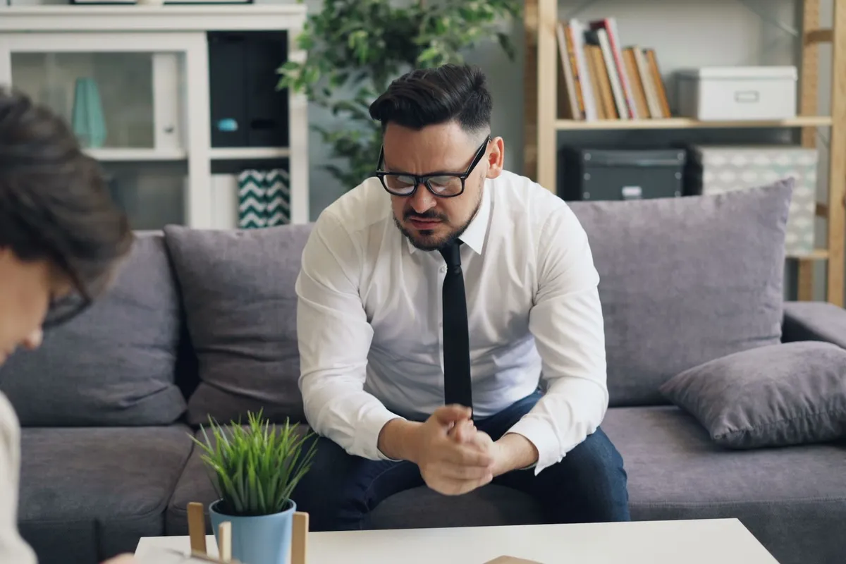 A man sitting across from a sex addiction therapist in a counseling session in daylight