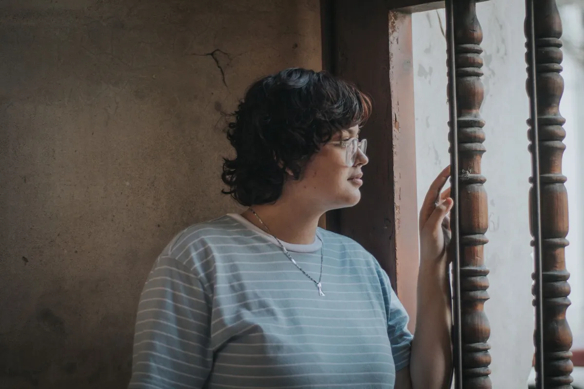 A woman looking out a window, thinking through the signs of a cheating husband