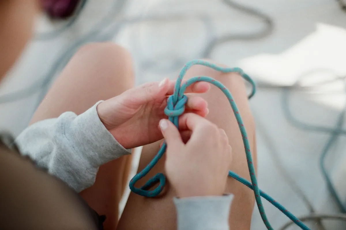 Two hands gripping a knotted rope, an image of the signs of trauma bonding