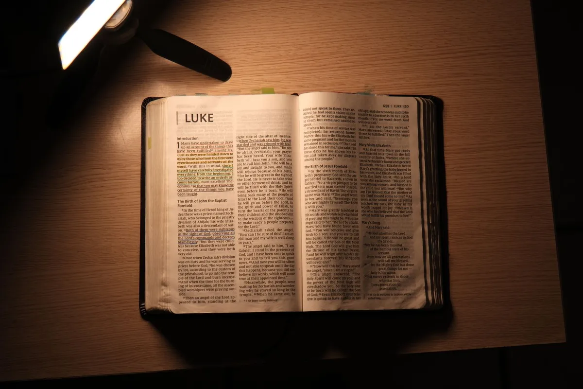 An open Bible on a desk under a lamp