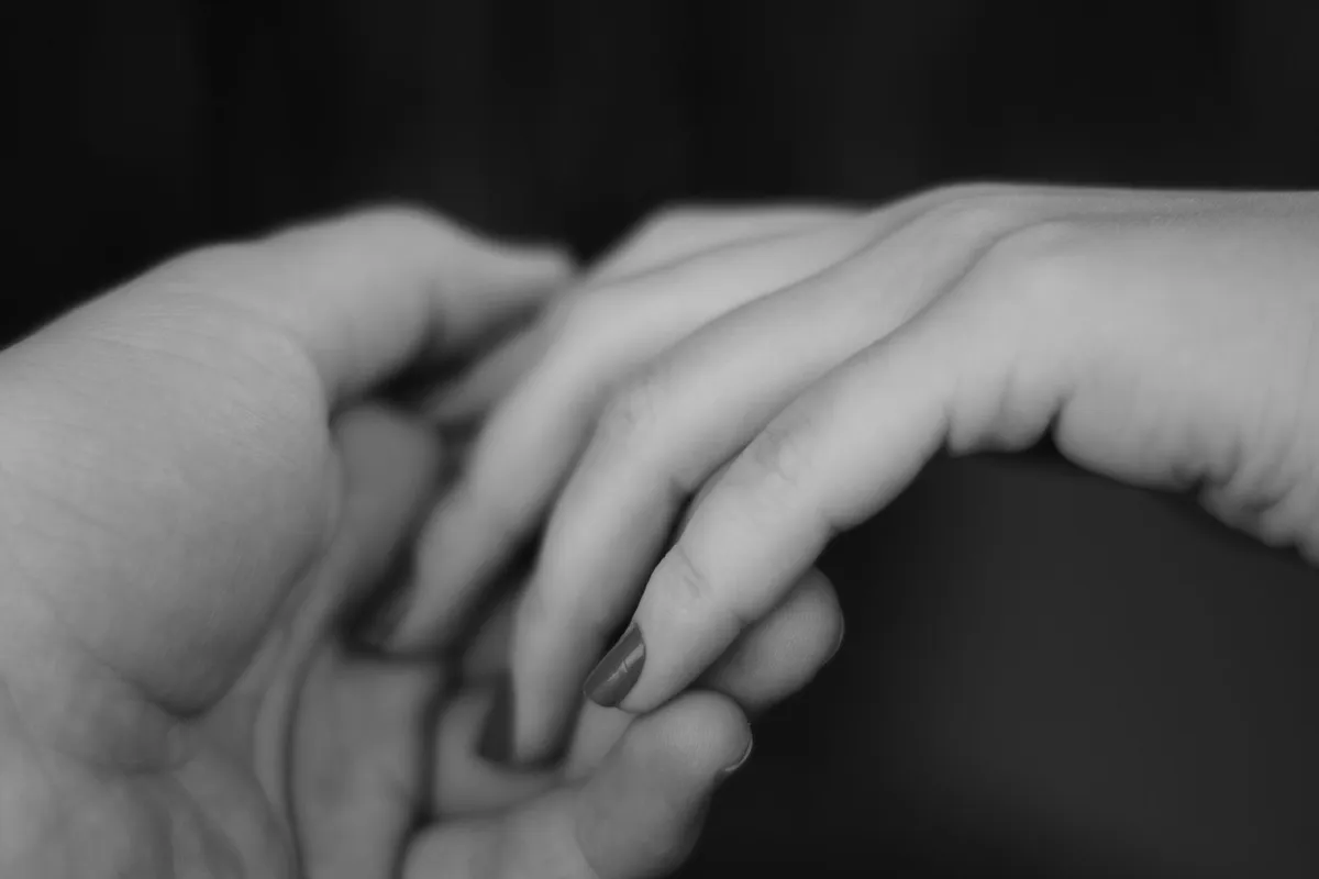 A black and white close-up of one hand reaching into another open palm