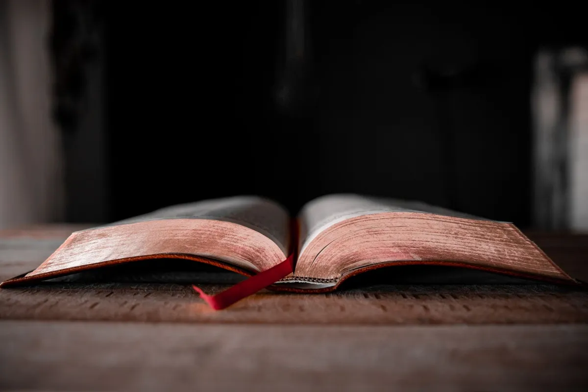 An old Bible lying open on a dark wooden table