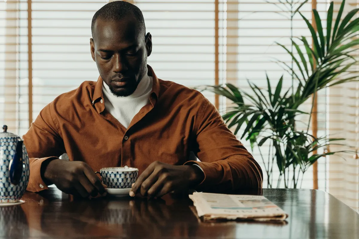 A man sitting at a table looking down at a cup of coffee