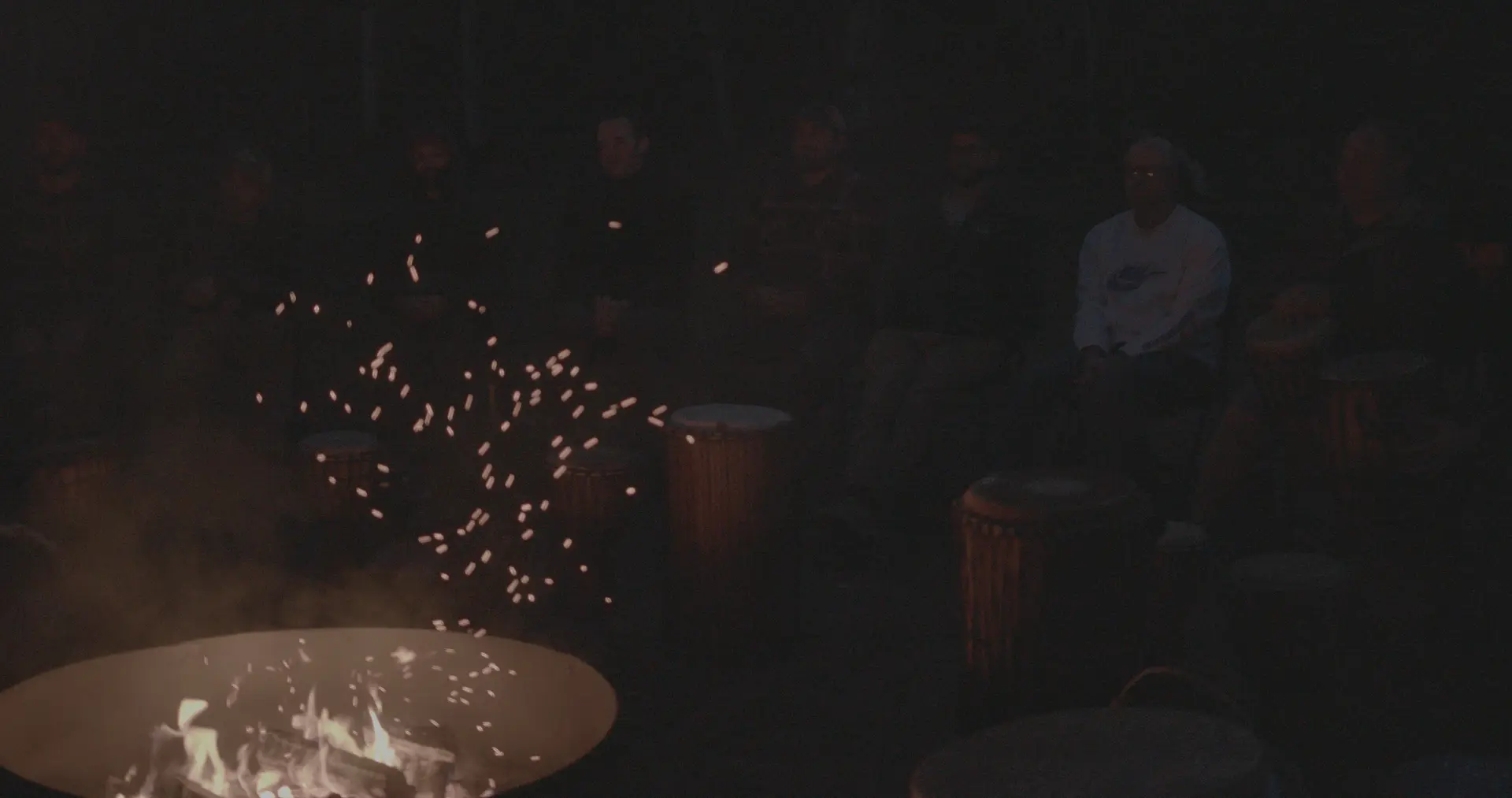 Men sitting around a fire at night at a retreat