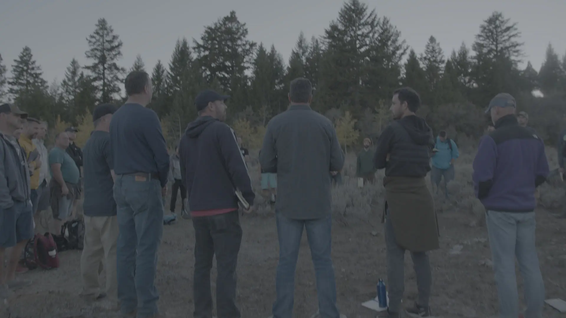 Men standing together in a circle in a forest clearing