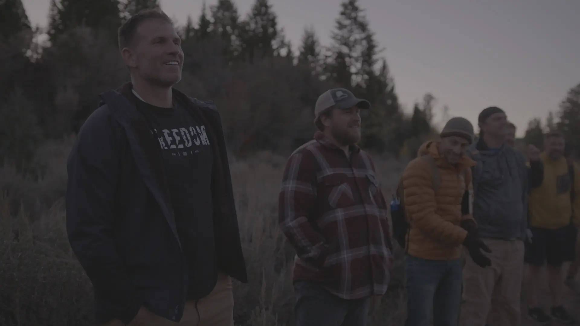 Men gathered together in a field at dusk during a retreat