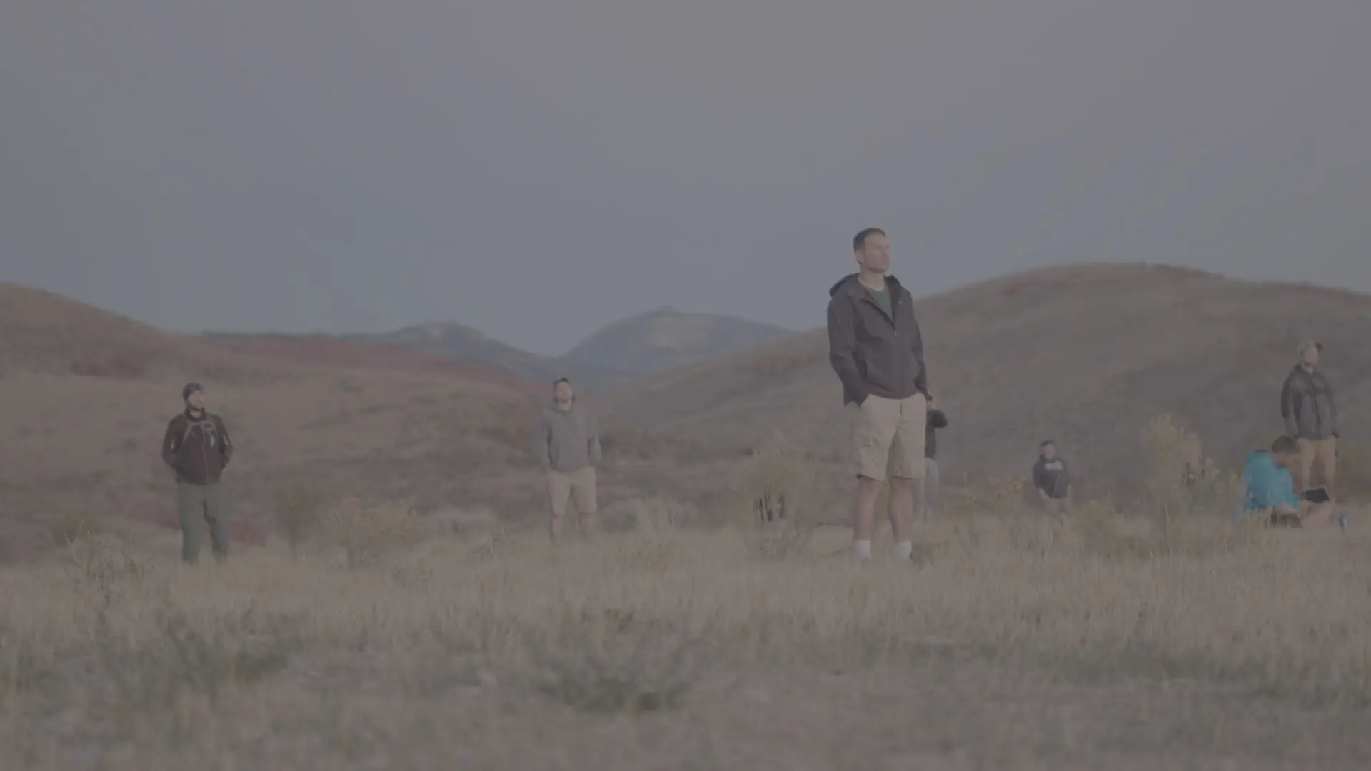 Men spread across an open field with mountains in the distance