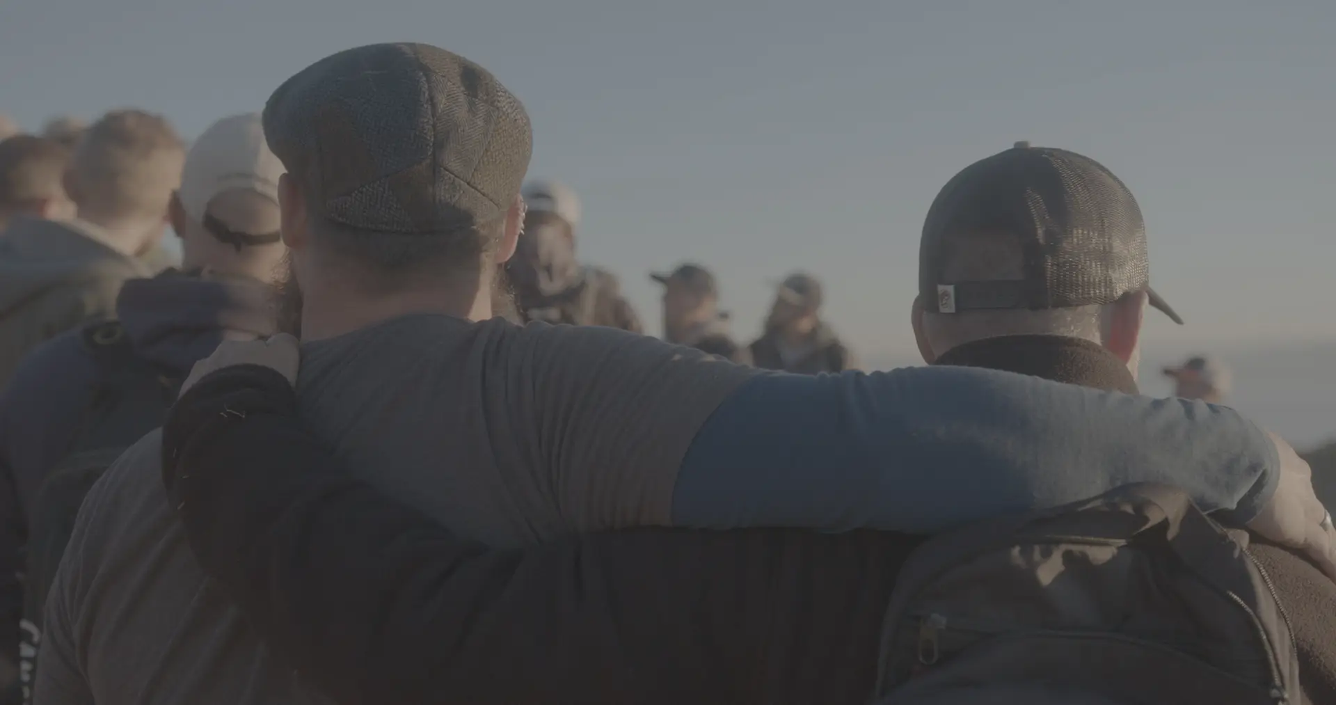 Two men with their arms around each other among the group at a retreat